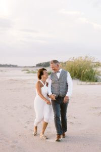 The bride and groom walk back from the beach together after their photo session portion of their Tybee Island Wedding.