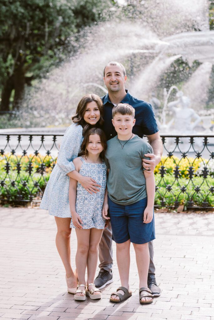 A family embraces in Savannah's Forsyth Park in front of its famous fountain.