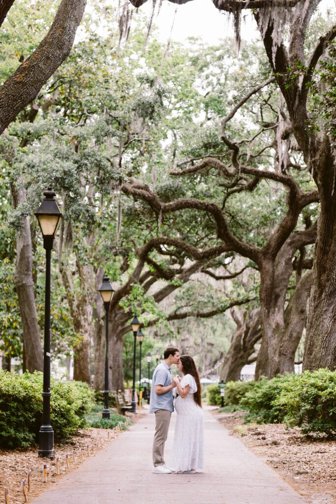 A couple holds hands amongst the Spanish moss covered live oaks in Forsyth Park.